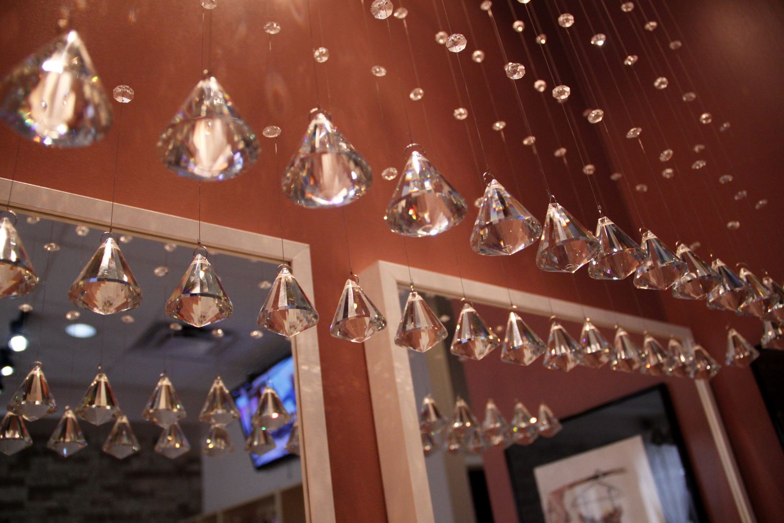 Crystal pendants hanging over the rose-pink manicure stations at Joy Spa & Nail